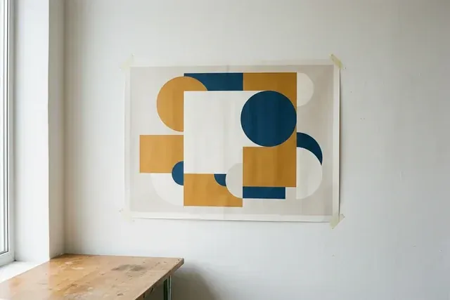 A printed poster of plain geometric shapes taped to a studio wall