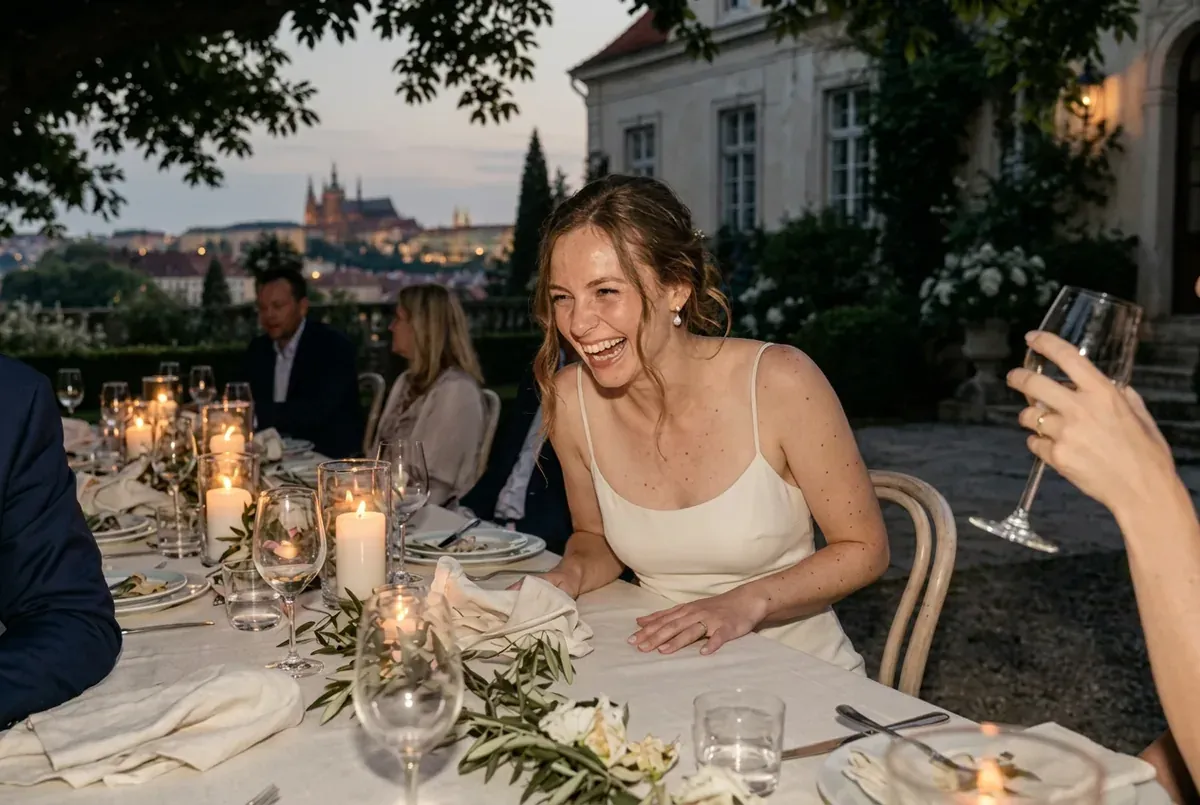 Anna laughing at the long dinner table in the garden, a glass raised beside her
