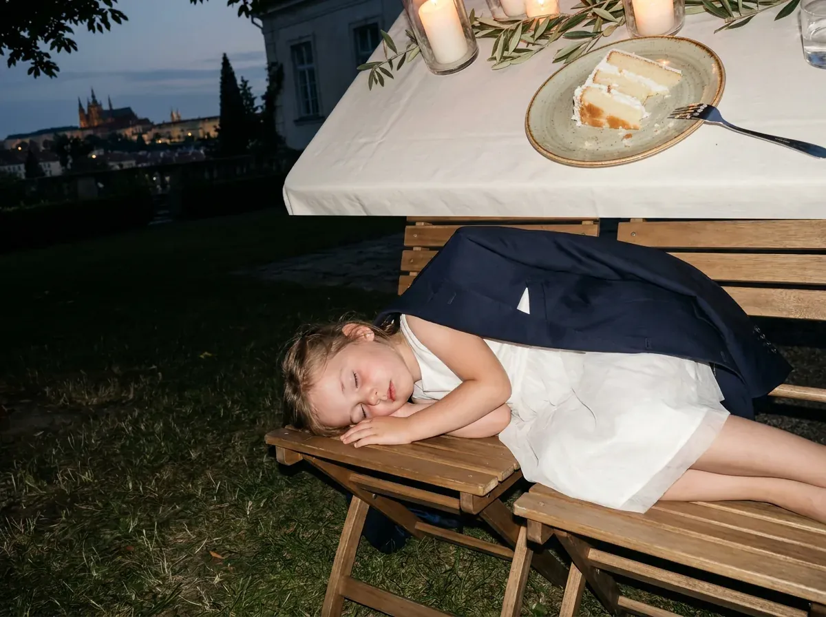 A little girl asleep across two garden chairs under a suit jacket