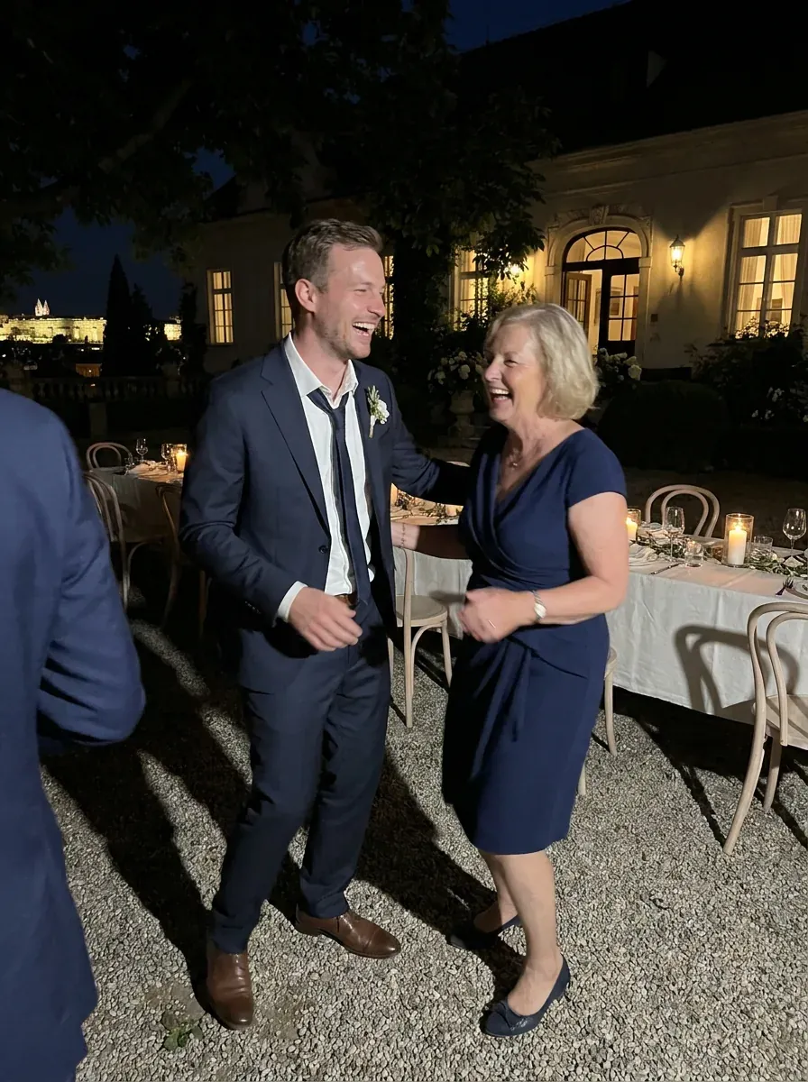 Petr laughing as he dances with his aunt on the gravel terrace at night